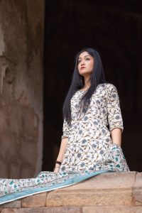 Portrait of a woman wearing an elegant Anarkali dress, looking upwards indoors.